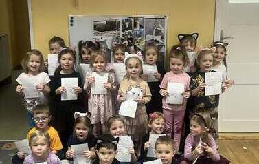 Grupa dzieci prezentująca zdjęcia swoich kot&oacute;w oraz dyplomy