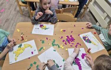 Dzieci wykonują pracę plastyczną - dinozaura