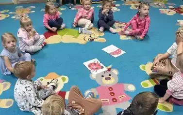 Grupa maluszk&oacute;w siedzi w kole