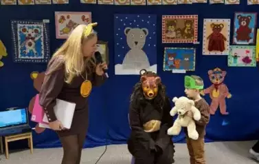 Nauczycielka, dziecko trzymające misia oraz nauczycielka przebrana za misia.