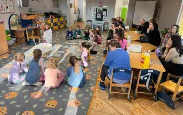 Dzieci biorące udział w zajęciach, rodzice siedzący przy stolikach