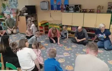 Rodzice z dziećmi siedzą w kole