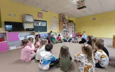 Dzieci siedzą w kole wraz z panią psycholog