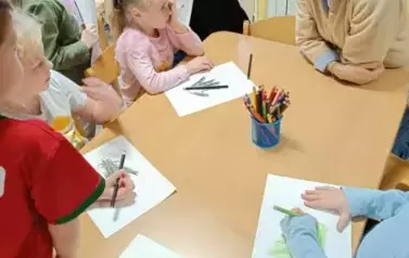 Dzieci rozmawiają z panią psycholog przy stoliku