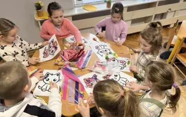 Dzieci wyklejają koty kolorowym papierem przy stoliku