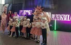 Dzieci z organizatorami, jury , wychowawcami i jeżem na tle dekoracji 