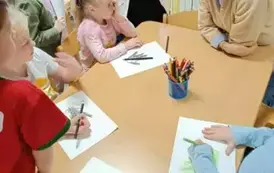 Dzieci rozmawiają z panią psycholog przy stoliku