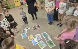 Dzieci z paniami tworzą sieć z kłębka wełny