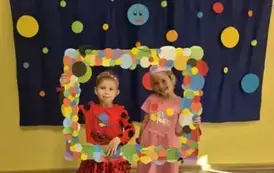 Dwie dziewczynki pozujące w ramce w kropki na tle kropkowej dekoracji