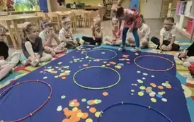 Dzieci wkładające papierowe k&oacute;łka do dużych obręczy
