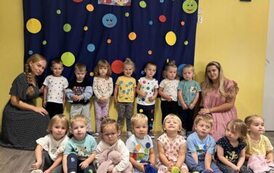 Grupa dzieci z wychowawcą na tle dekoracji 