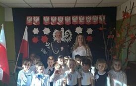 Grupa dzieci z wychowawcą i żołnierzem na tle dekoracji