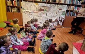 Dzieci słuchają książki czytanej przez panią bibliotekarkę
