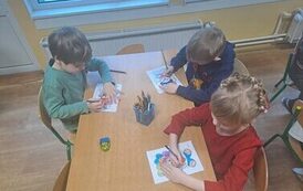 Dzieci kolorują rysunki przy stoliku