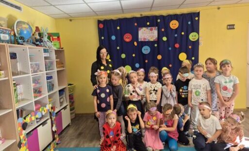 Grupa dzieci z wychowawczynią na tle dekoracji