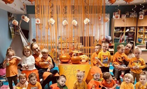 Grupa maluszków z panią na tle dekoracji przebrani za dynie