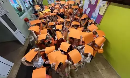 Dzieci trzymające pomarańczowe kartki