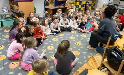 Dzieci siedzące w kole z pania bibliotekarką